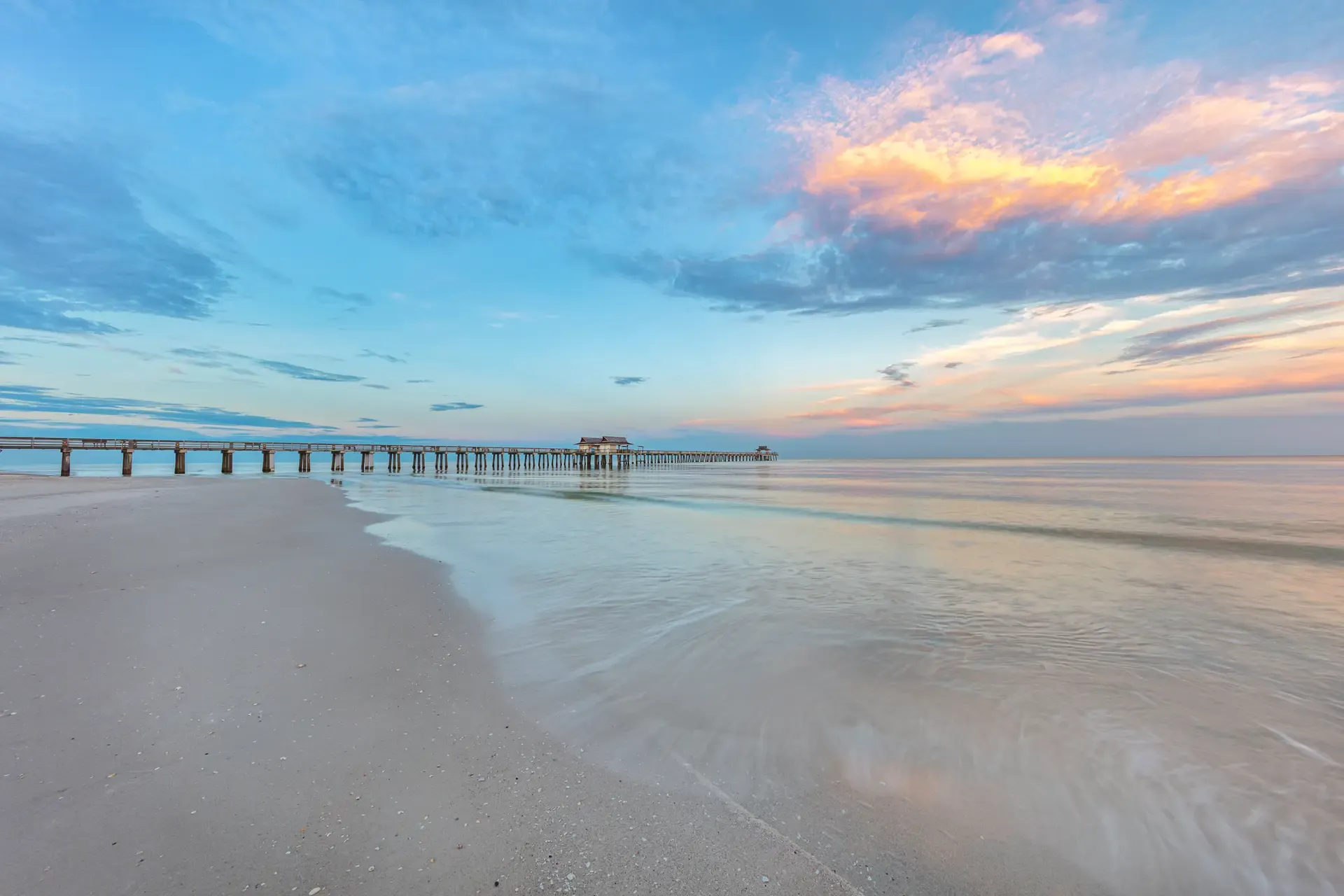 Serene beach at sunset with pier