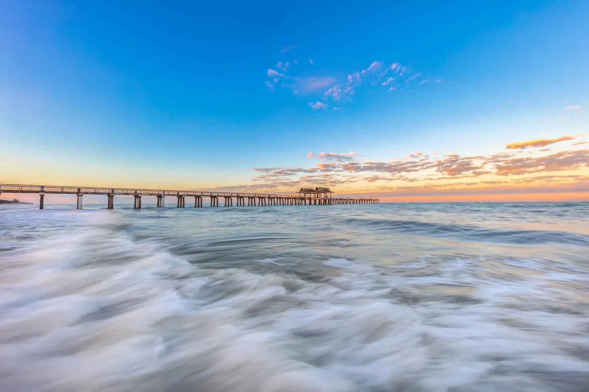 Sunset over calm ocean pier