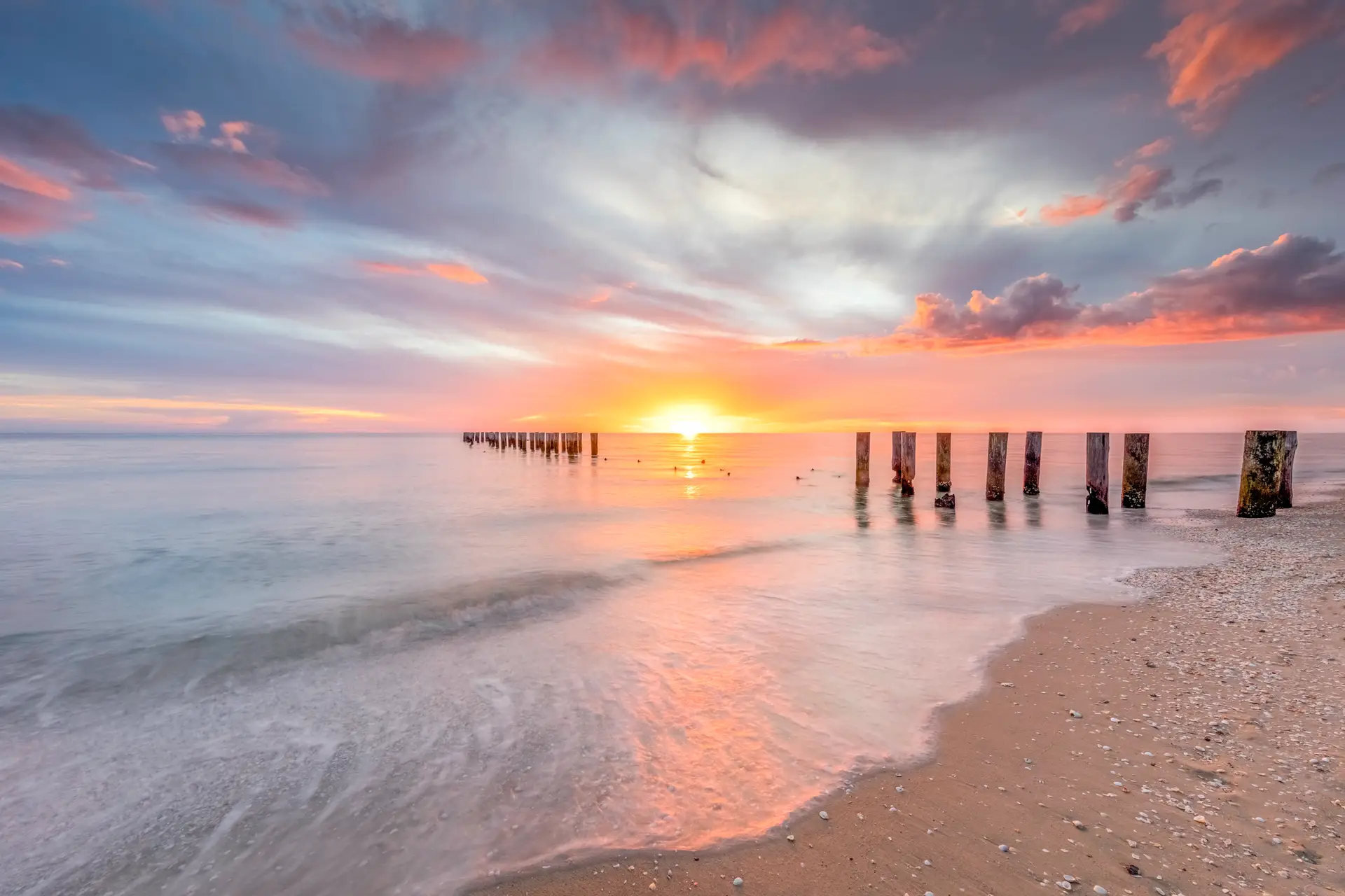 Sunset over calm ocean with pilings
