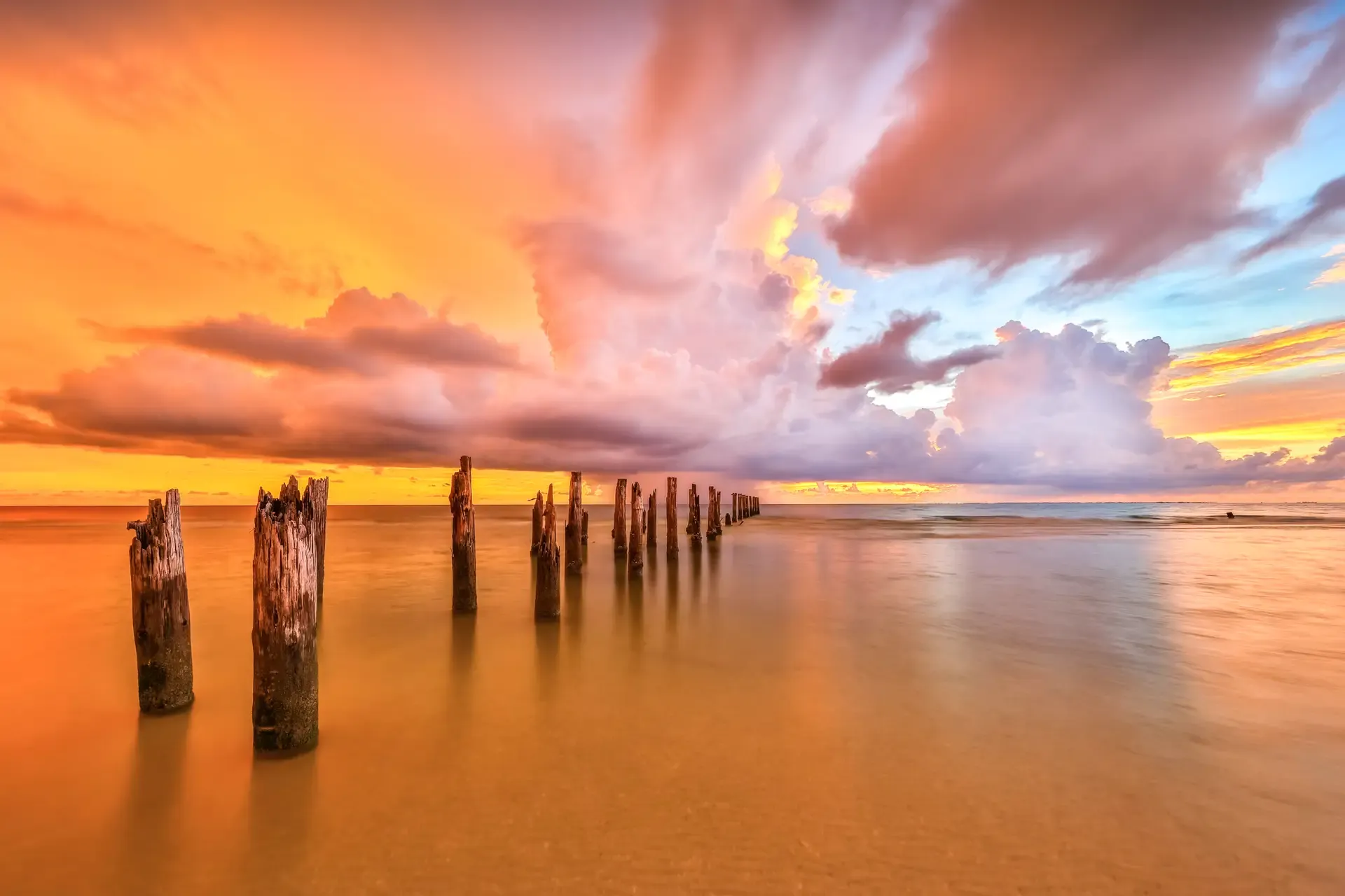 Sunset over calm ocean with pilings