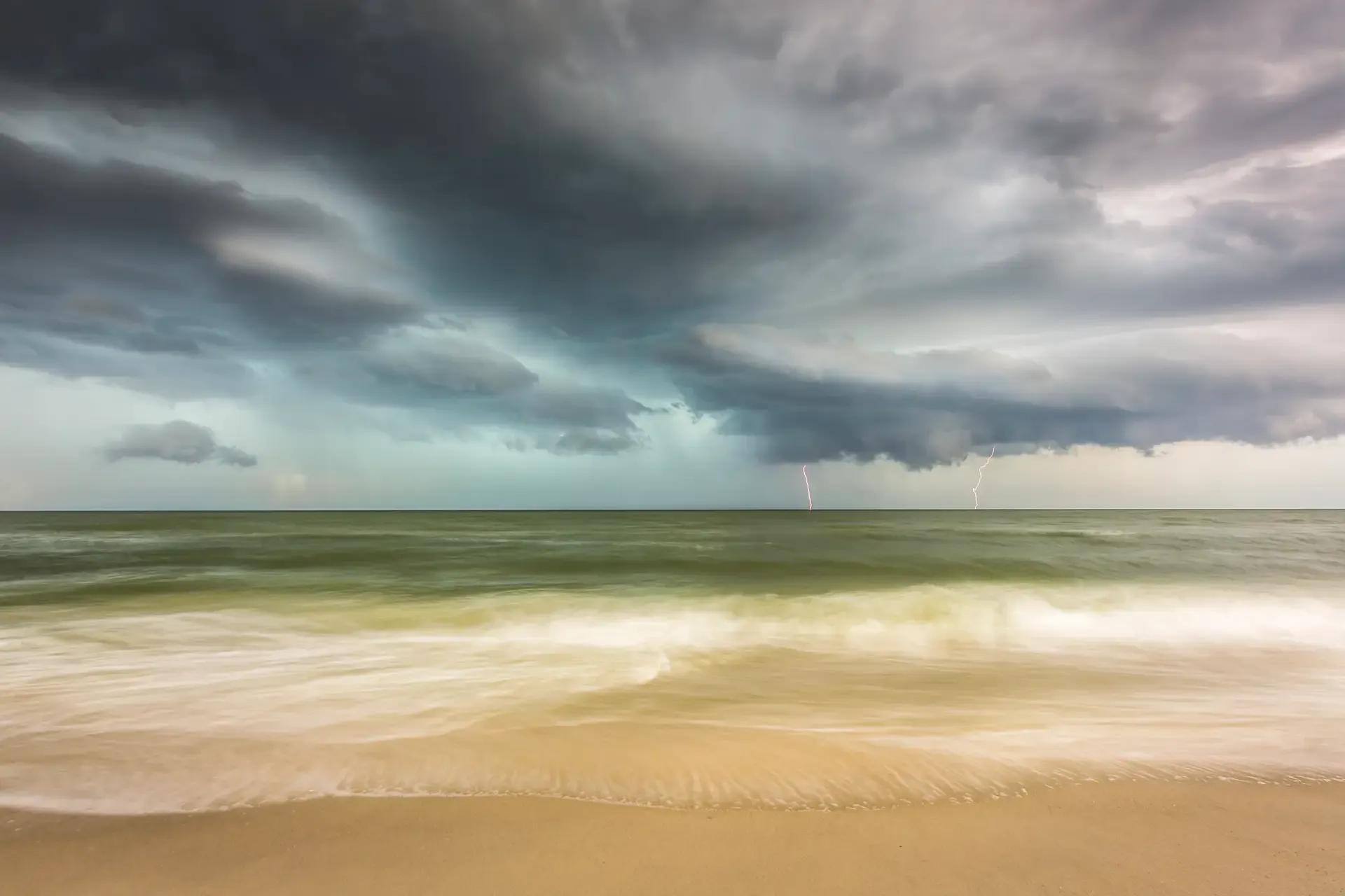 Stormy ocean with distant lightning strikes