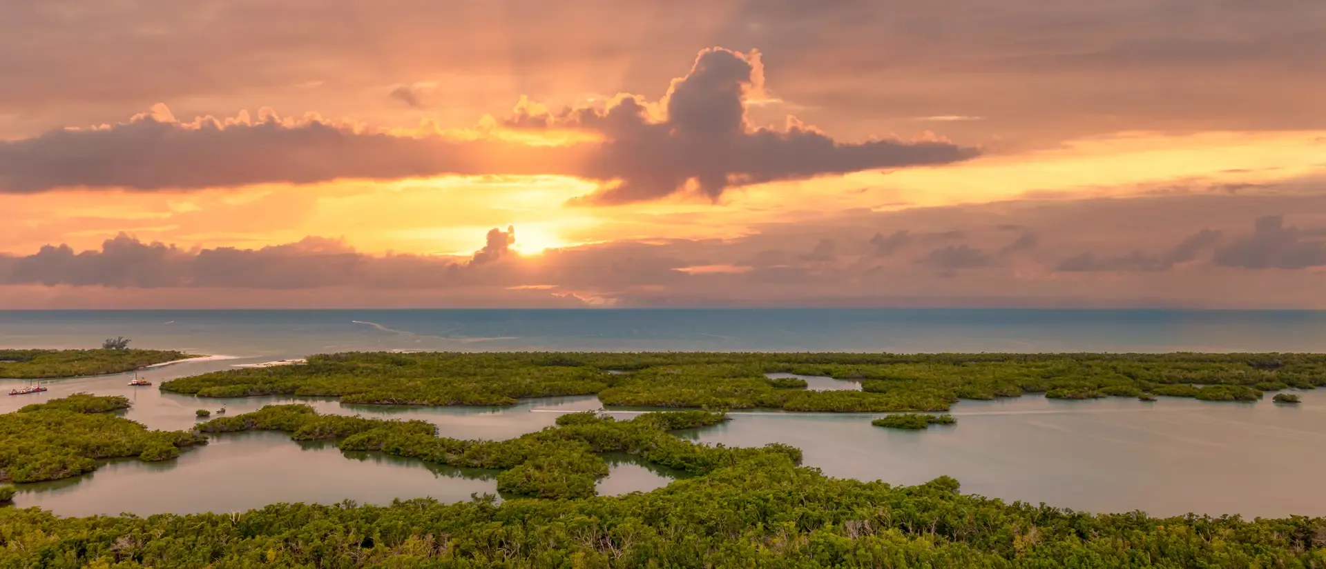Sunset over a marshland with vibrant clouds and reflective water.