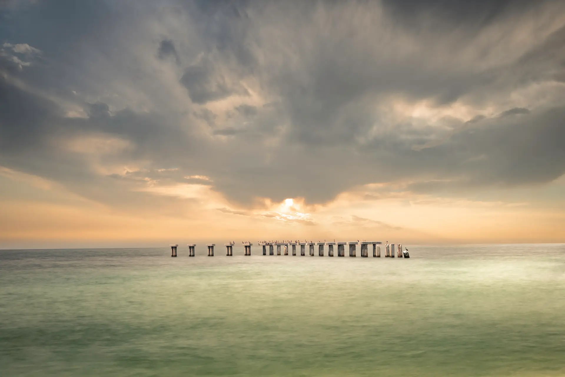 Serene pier under dramatic sunset sky