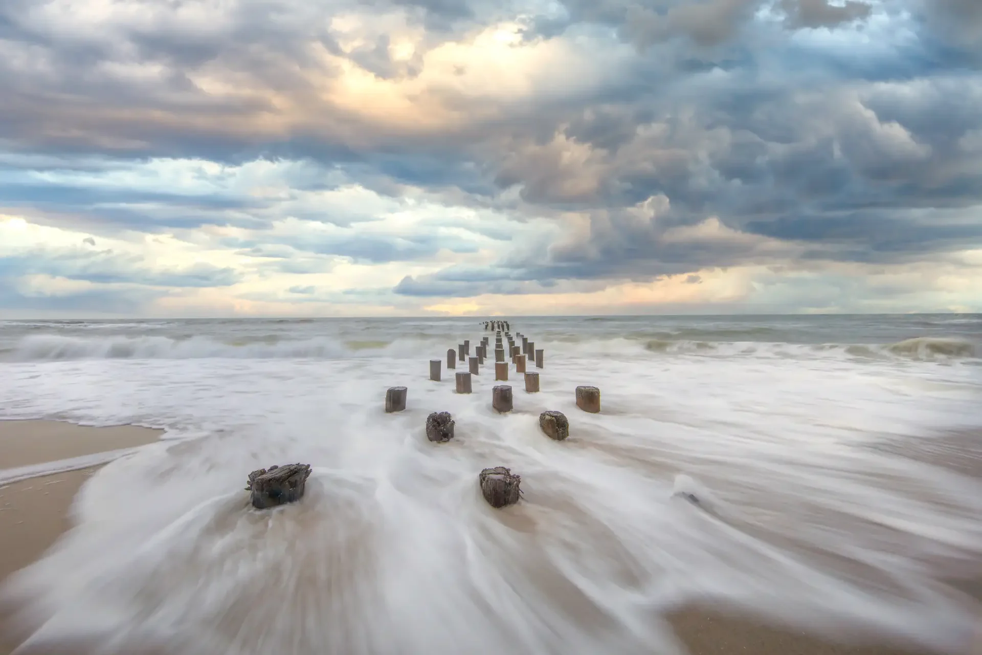 Wooden posts stretching into the sea under a dramatic sky.