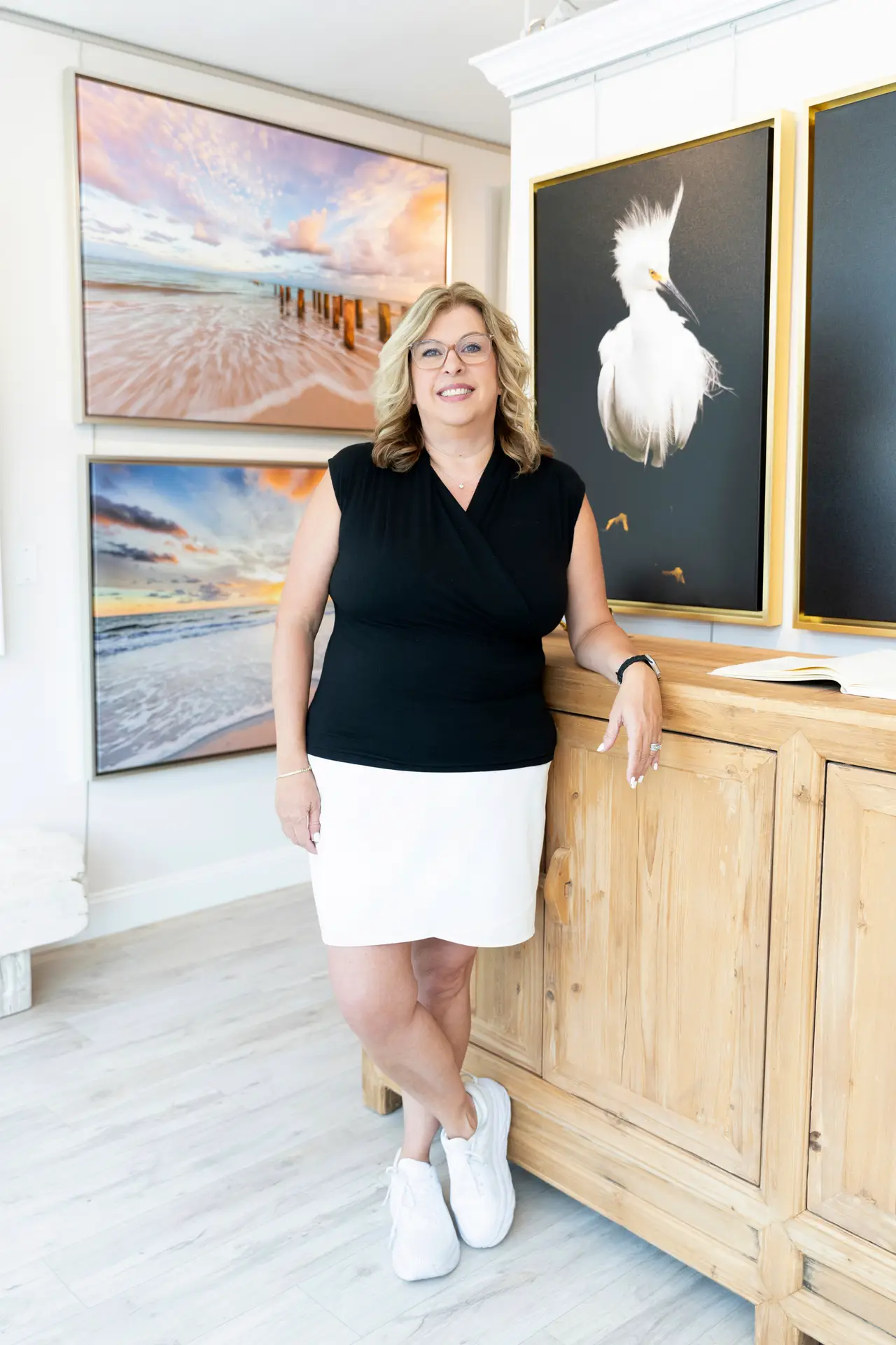 Woman posing casually by a wooden counter in an art gallery.