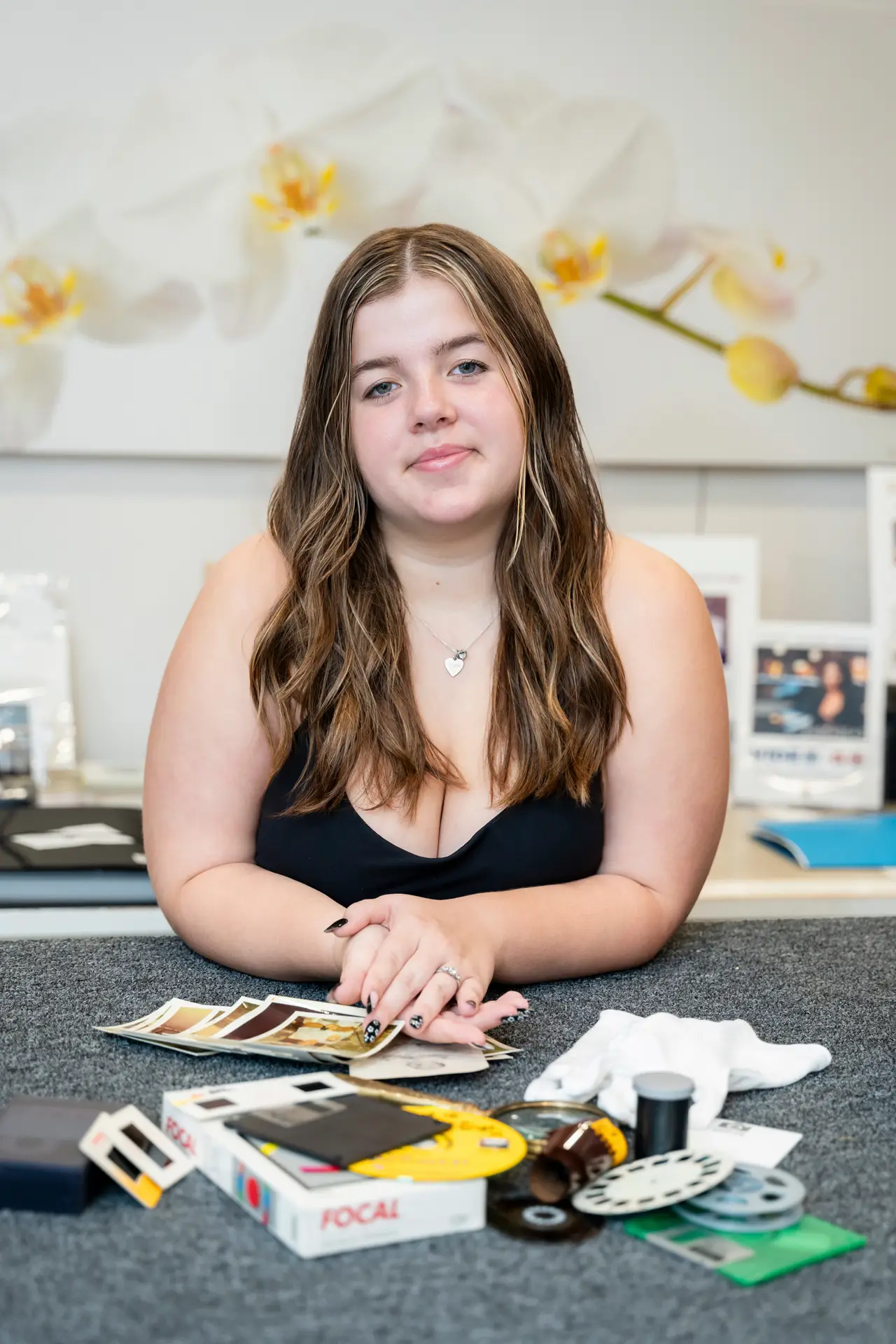 Young woman with long hair sitting at a table with tarot cards and crystals.