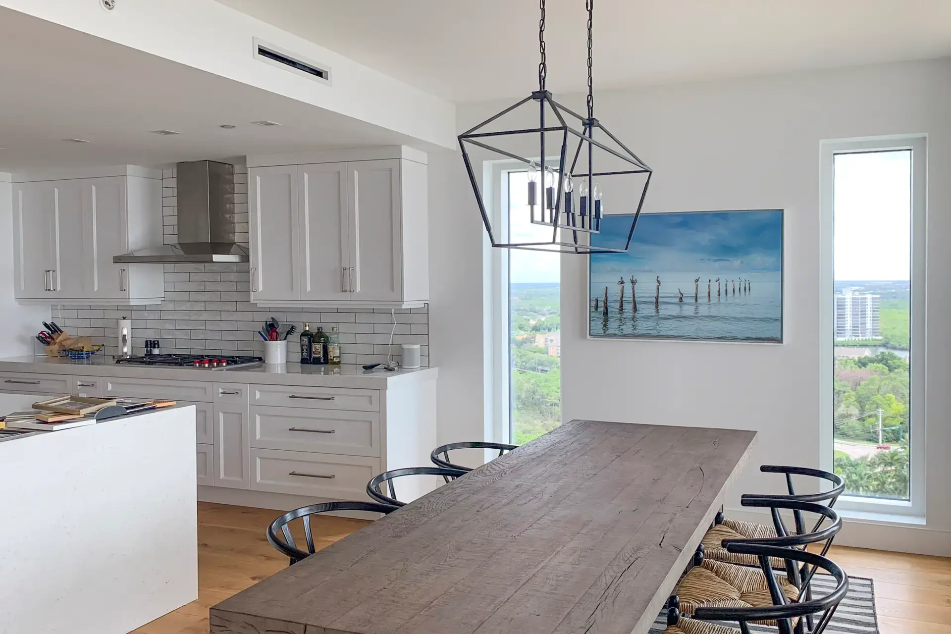 Modern kitchen with a wooden dining table and geometric pendant lights.