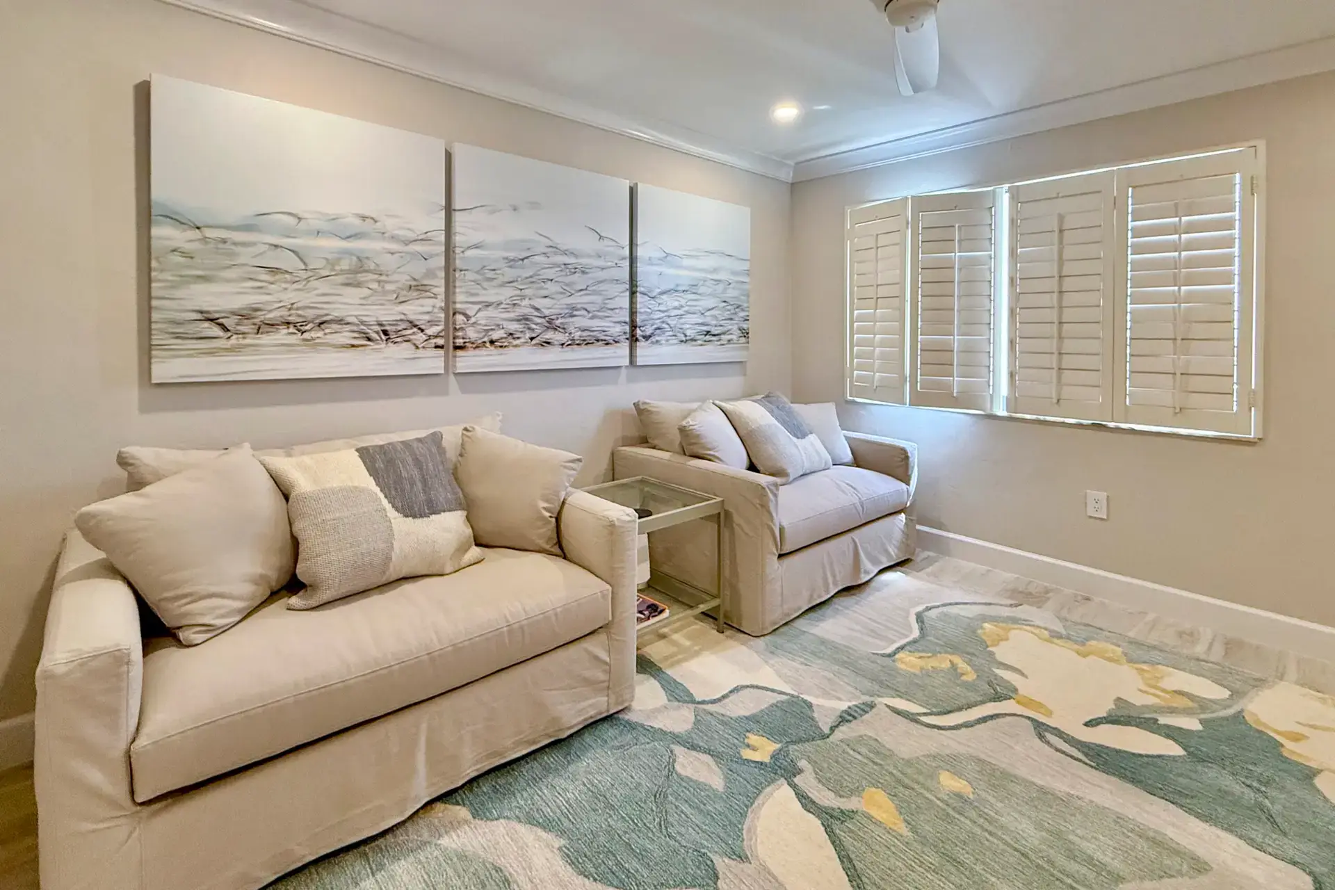 Cozy living room with beige sofas and floral rug.