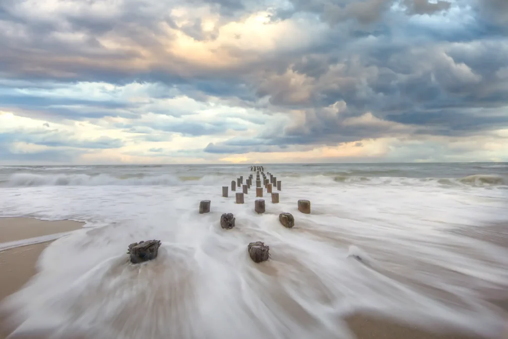 Wooden posts stretching into the sea under a dramatic sky.