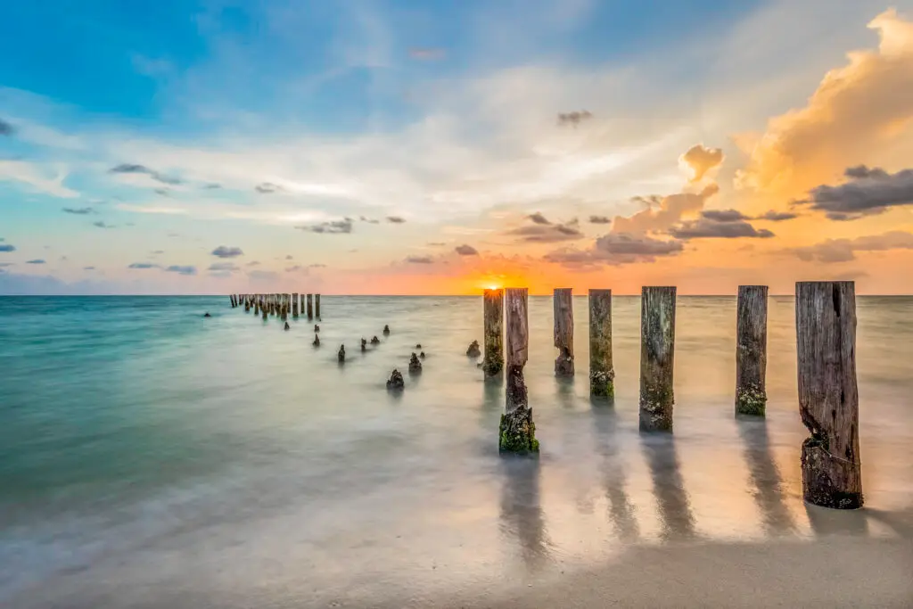 Sunset over calm ocean with pilings