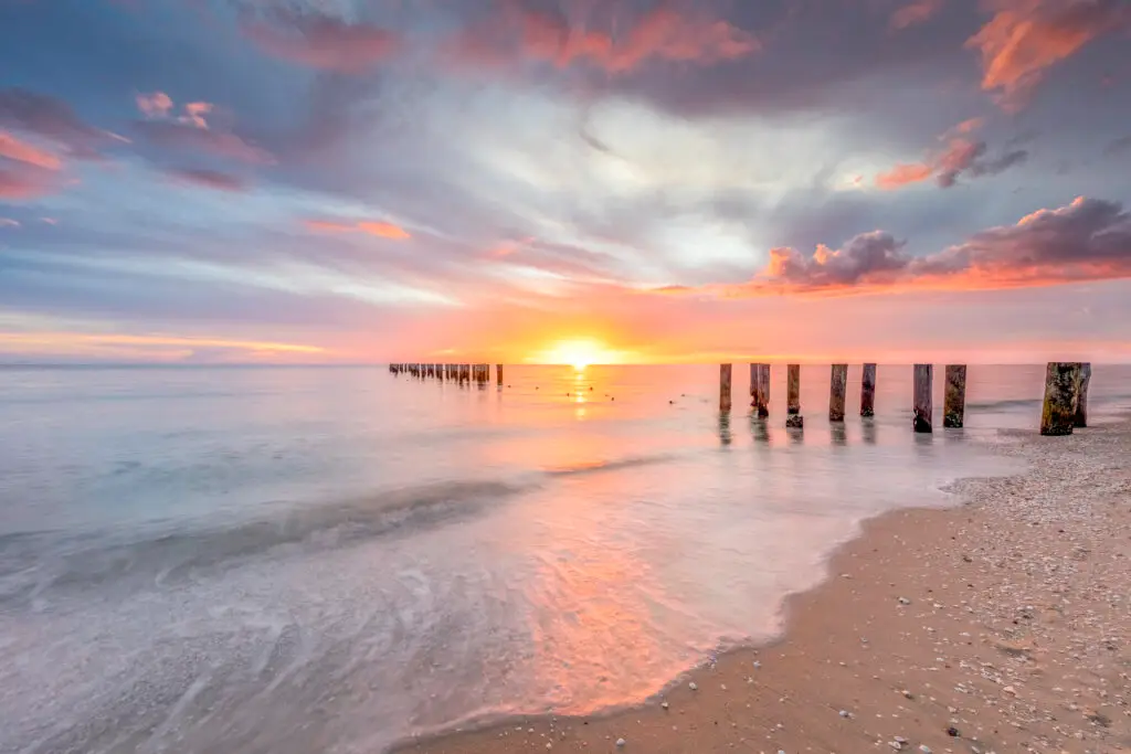 Sunset over calm ocean with pilings